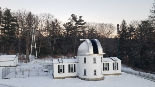 Shattuck Observatory and surrounding observing area covered with snow on a sunny day.