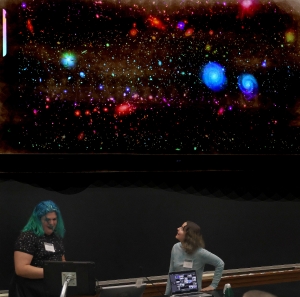 Kai Herron and Sasha Campana underneath a screen displaying Rubin Observatories LSST First Light