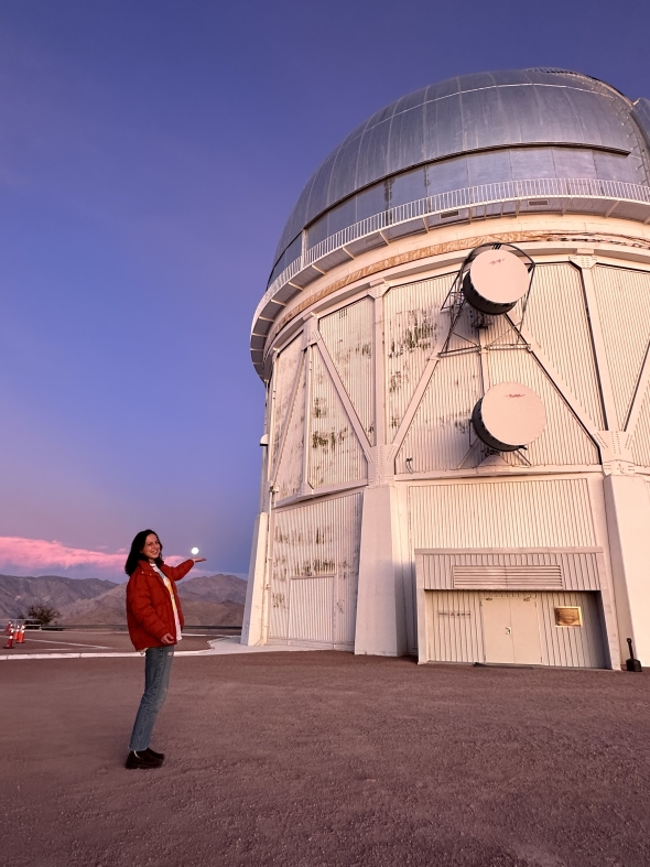 Ella Marin '25 stands in front of the Cerro Tololo Inter-American Observatory "holding" the moon. 