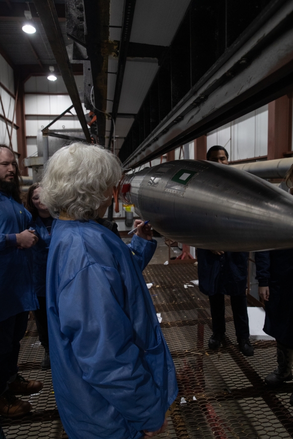 Kristina Lynch signing the nose cone of the 397 GNEISS rocket.